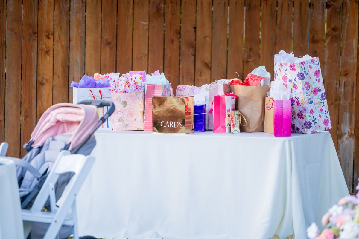 A table filled with colorful gift bags and a stroller at an outdoor event. Stock Photo.