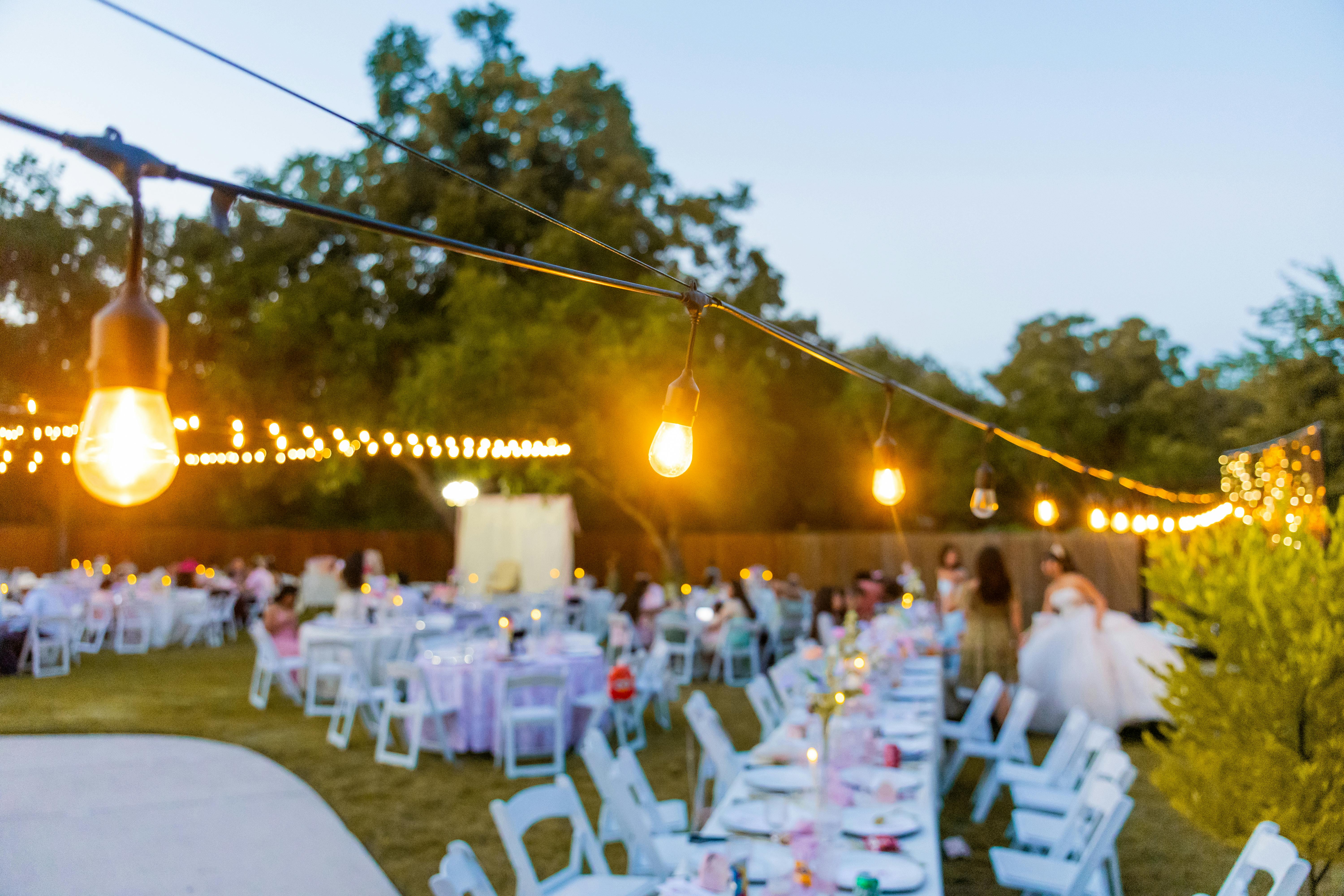 Charming outdoor wedding reception at sunset with string lights.