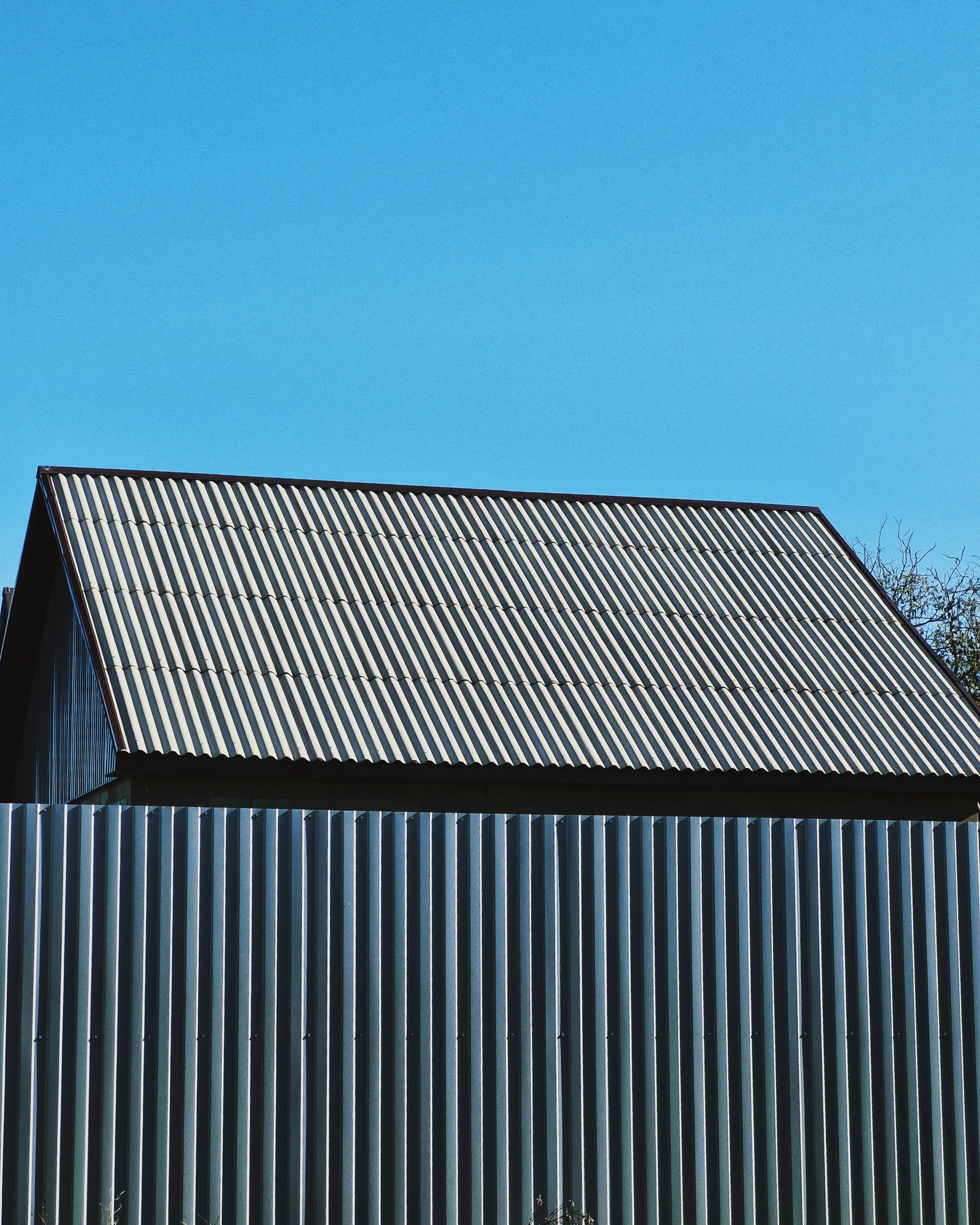 Minimalist standing-seam metal roof against a clear blue sky