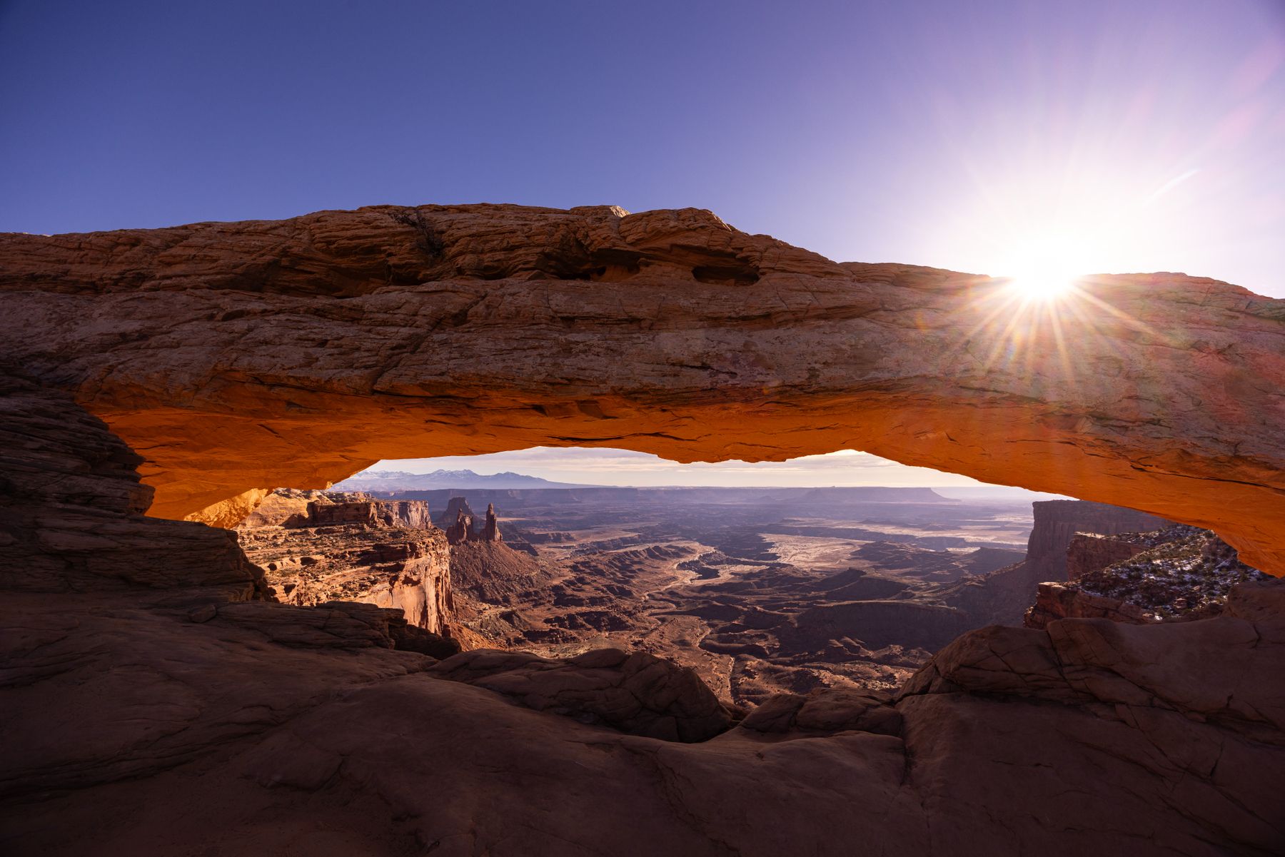 Sunrise light through Mesa Arch over a canyon