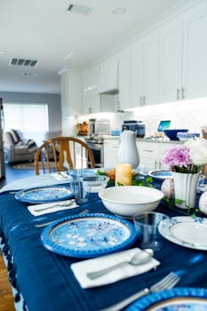 A beautifully set dining table with blue dinnerware and floral decor in a modern kitchen.
