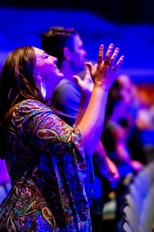Free Woman enjoying live music at a vibrant concert with blue stage lights. Stock Photo