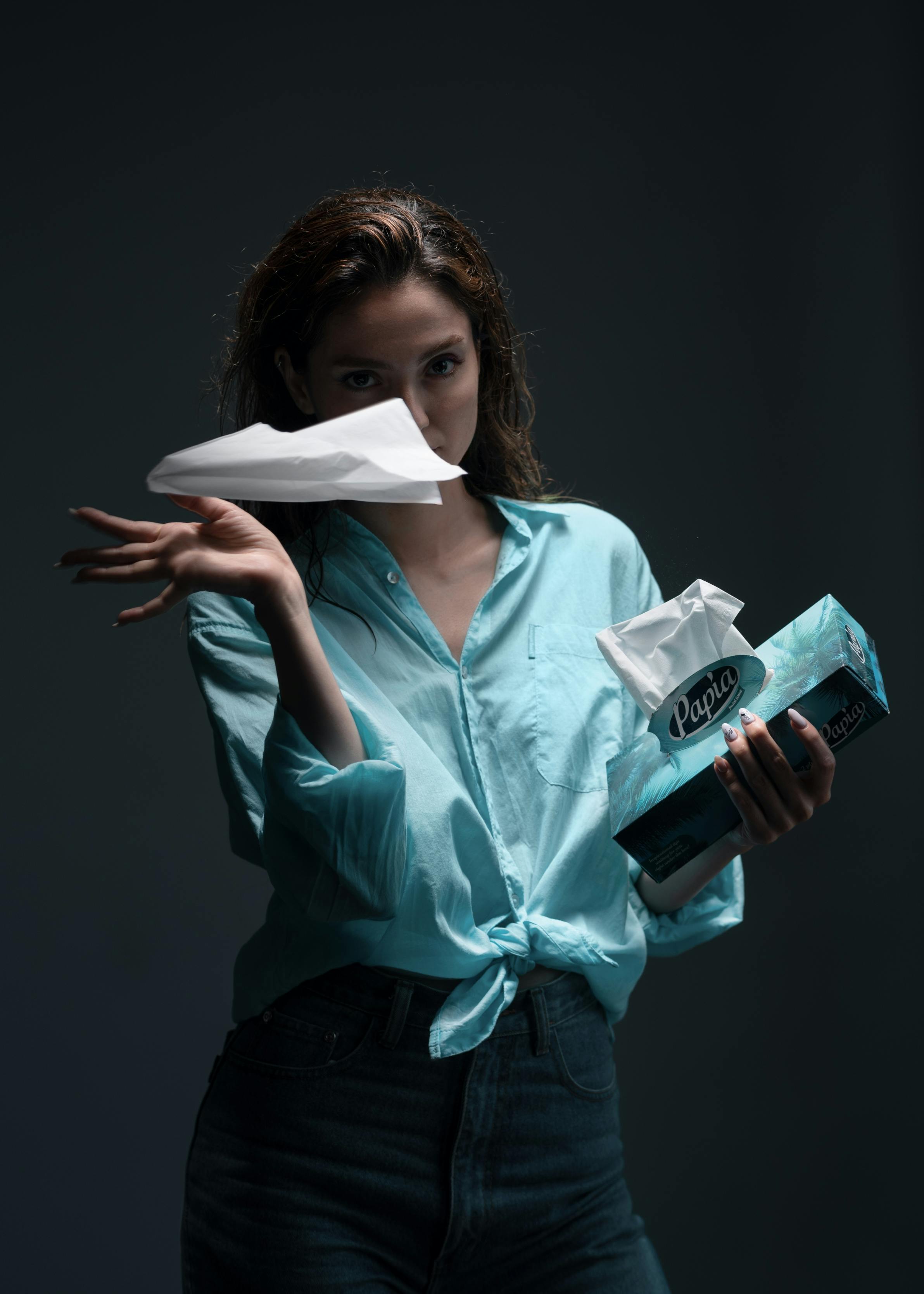 Gratuit Femeie în cămașă albastră aruncă dramatic șervețele, fundal întunecat. Fotografie de stoc