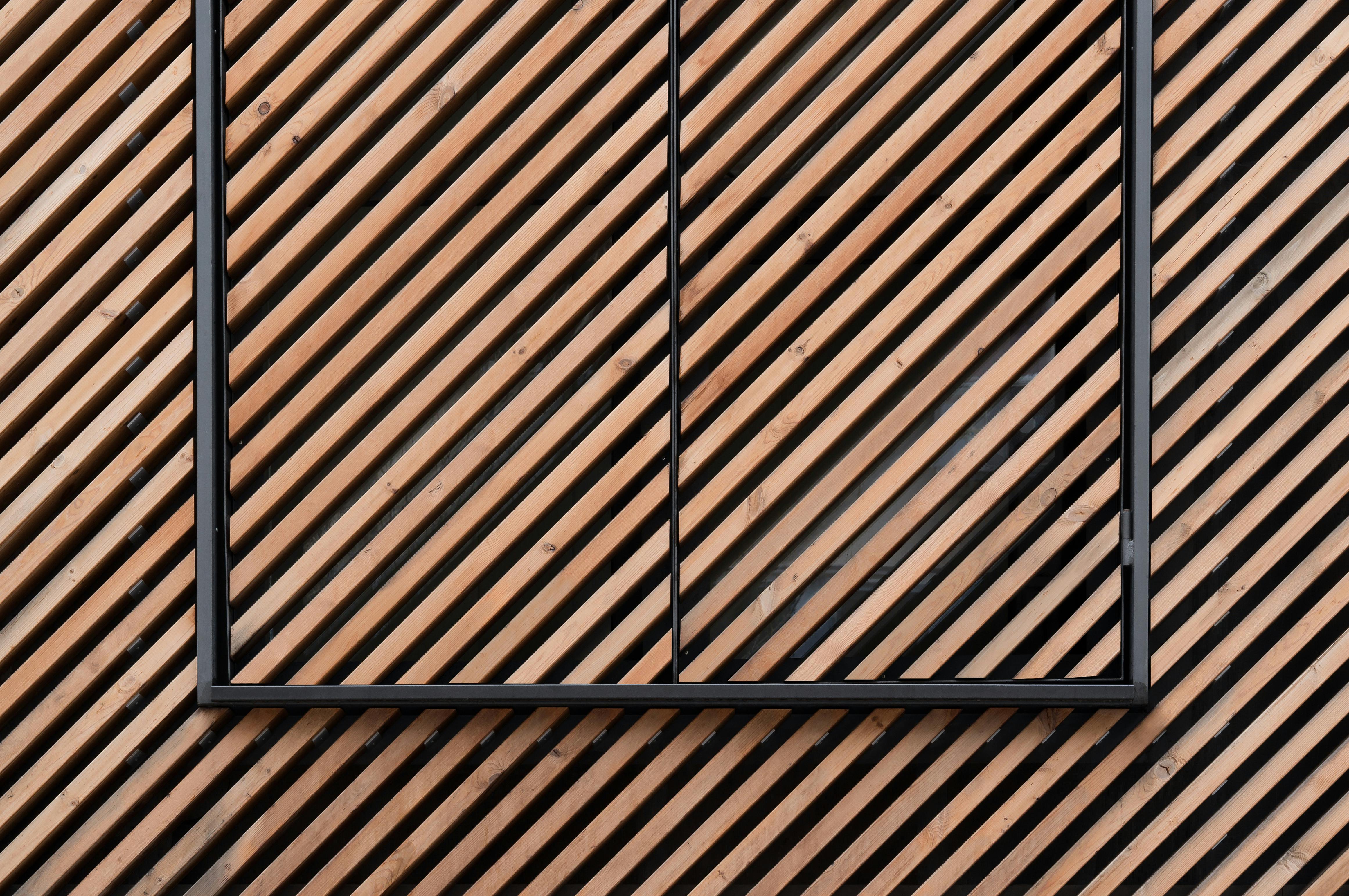 Kostnadsfria Minimalistisk arkitektur med en brun trävägg med ett diagonalt linjemönster och en svart fyrkantig ram. Stock foto