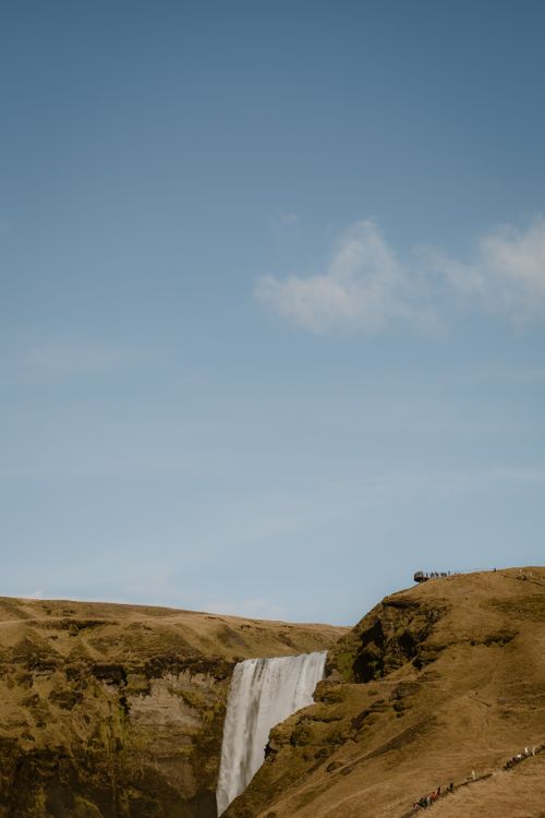 Free Beautiful waterfall cascading down a rustic landscape in Iceland under a blue sky. Stock Photo