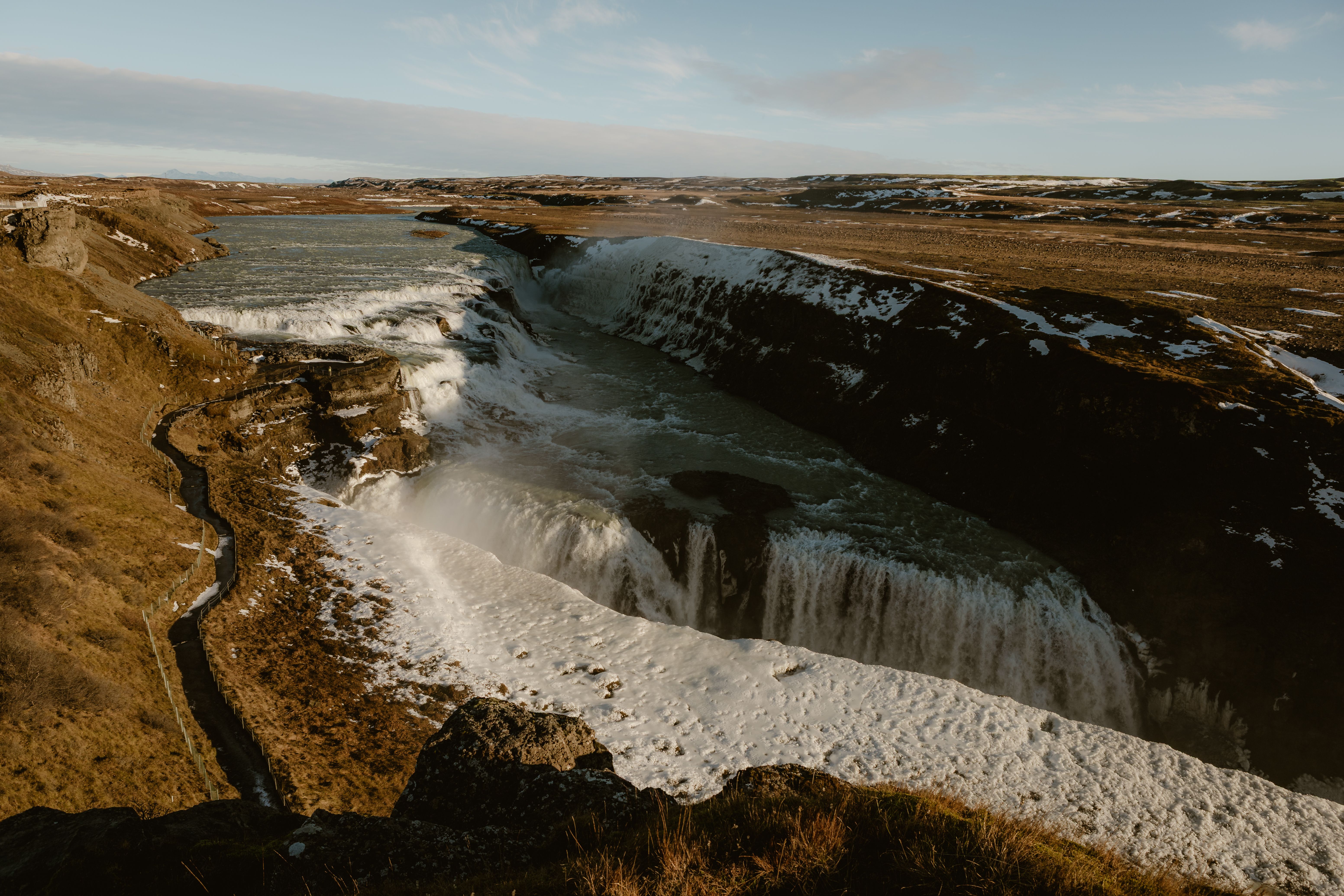 A stunning view of Gullfoss waterfall under a bright sky, showcasing its natural beauty and flowing water.