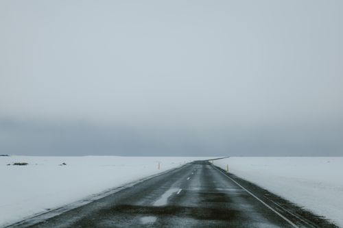 Free Desolate winter road stretching into the snowy horizon under an overcast sky. Stock Photo