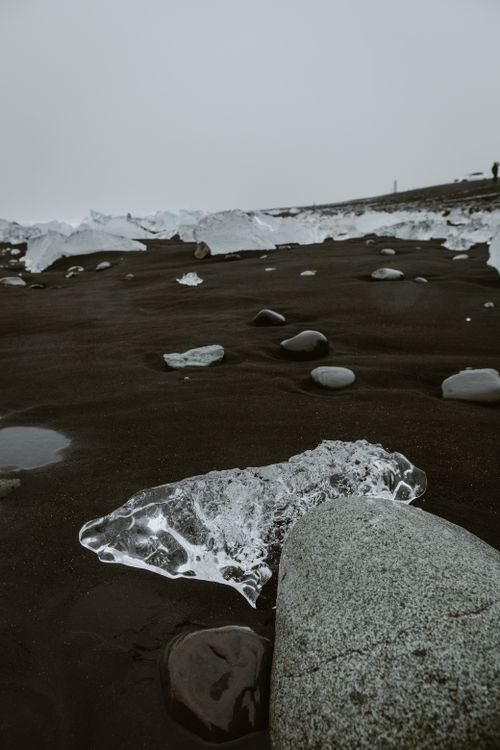 Free Stunning view of a black sand beach with ice formations and smooth stones, capturing nature's contrasts. Stock Photo