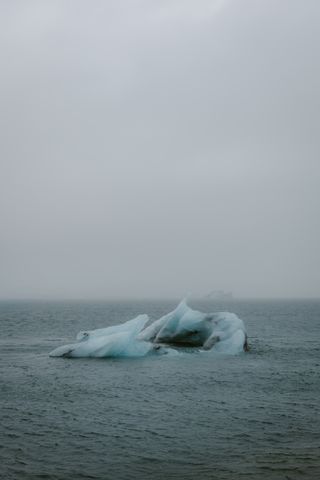 A lone iceberg in misty Arctic water — photo by Andreas Ebner on Pexels