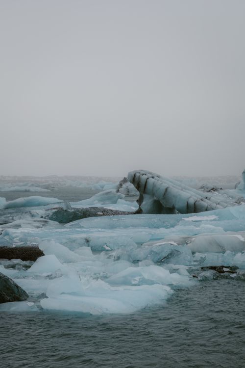 Free Stunning view of scattered icebergs in calm Arctic waters under an overcast sky. Stock Photo