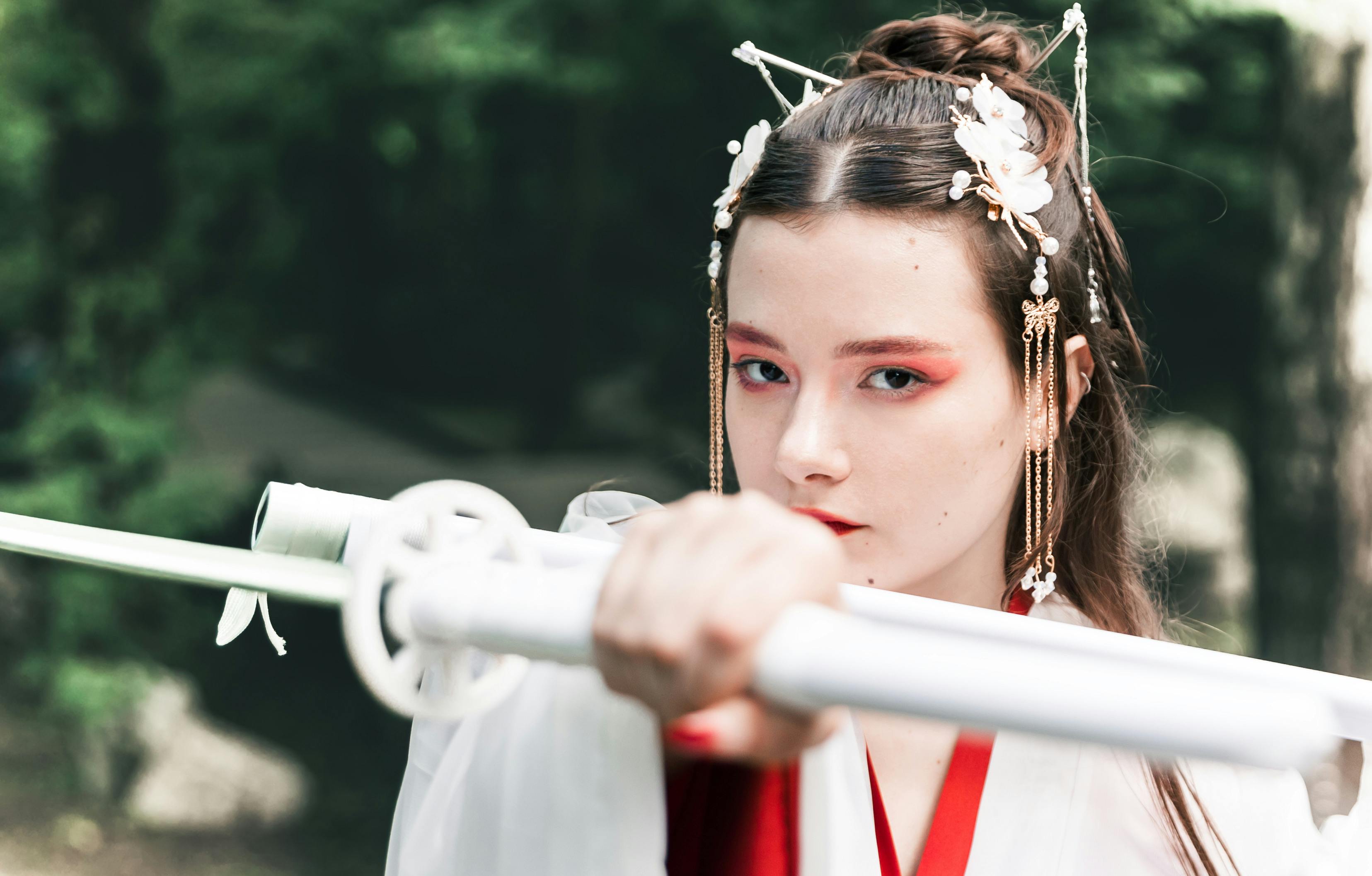 Young woman in traditional outfit posing with a sword, showcasing warrior spirit.