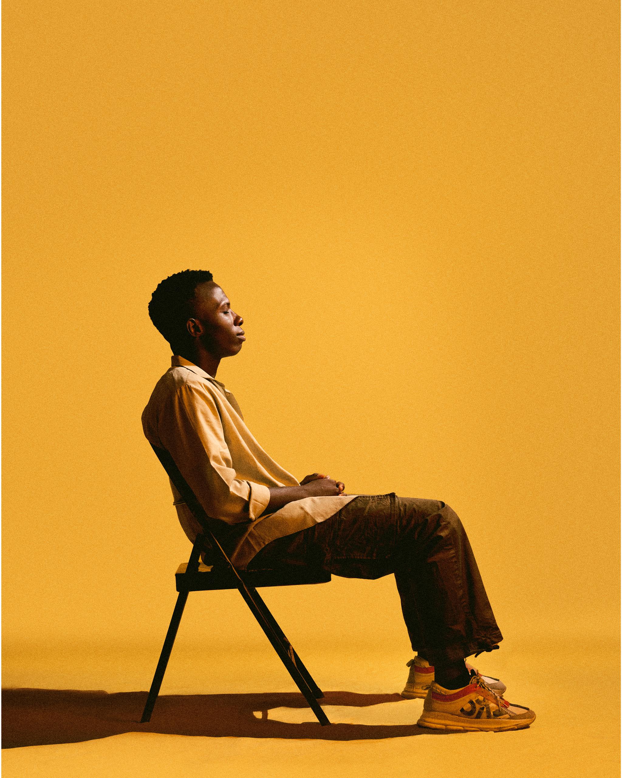 Silhouette of a person sitting on a chair against a vibrant yellow background, embodying solitude and contemplation.