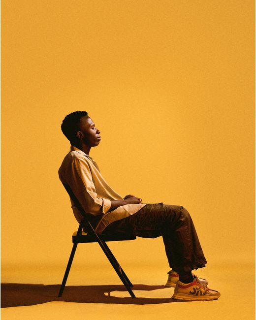 Silhouette of a person sitting on a chair against a vibrant yellow background, embodying solitude and contemplation.