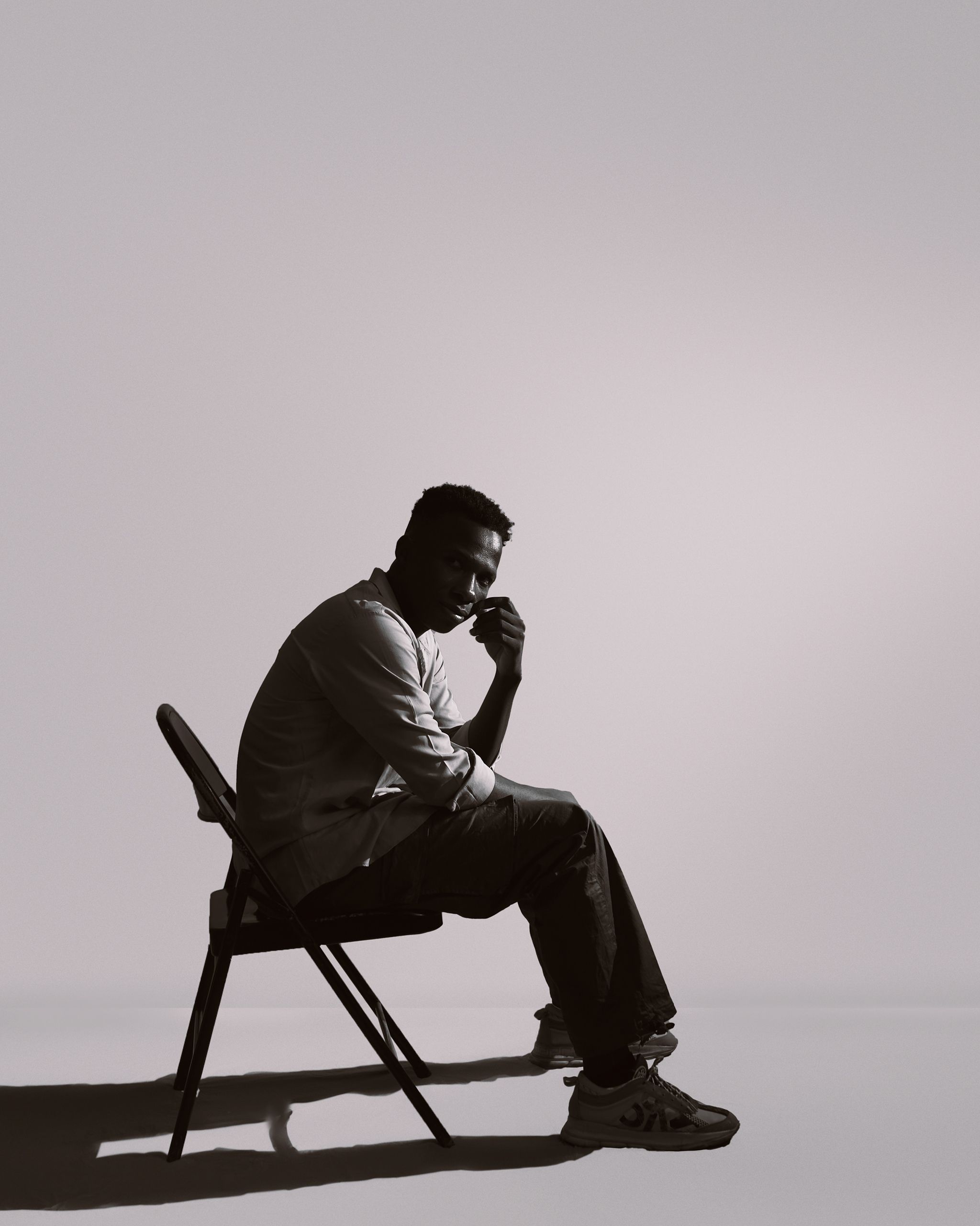 Silhouette of a pensive man seated in a chair, with dramatic lighting and shadow play.