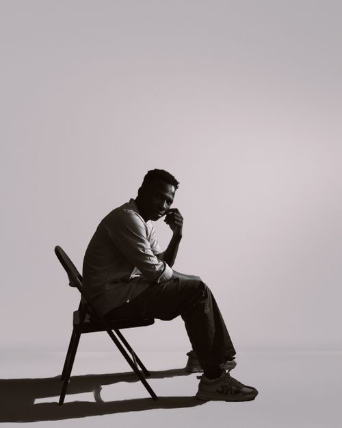 Free Silhouette of a pensive man seated in a chair, with dramatic lighting and shadow play. Stock Photo