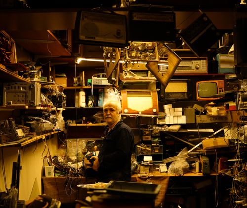 Free An elderly man in a cluttered workshop with vintage electronics and retro gadgets. Stock Photo
