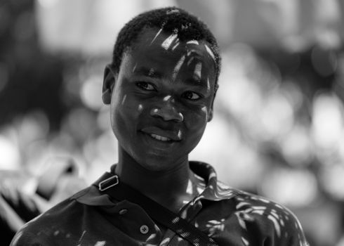 Captivating black and white portrait featuring artistic leaf shadows on a smiling face.