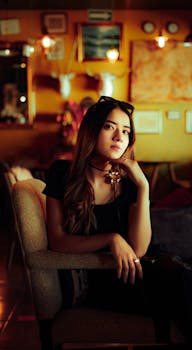 Stylish woman seated in a vintage cafe setting, exuding confidence and elegance.