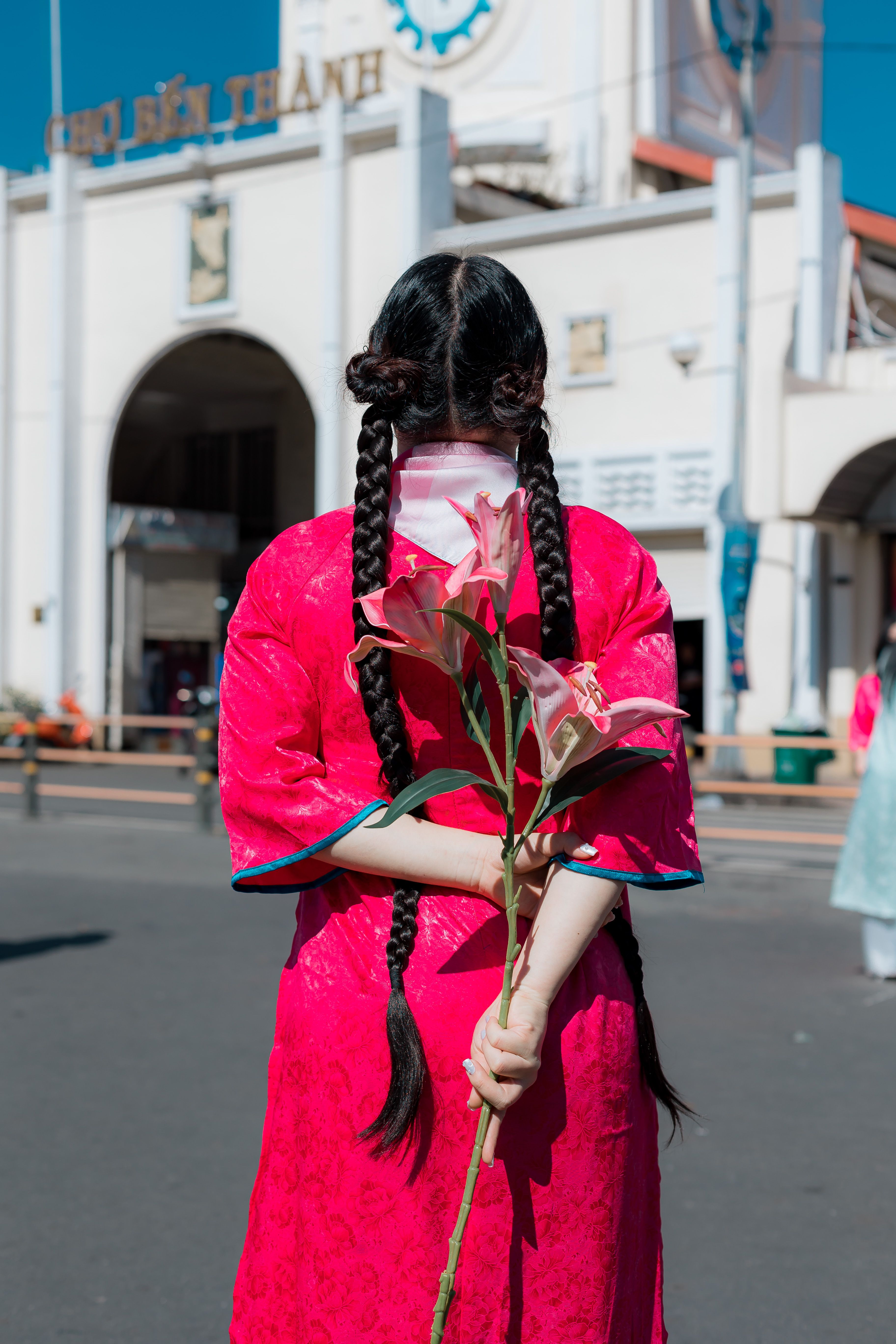 Woman in traditional dress holding lilies outdoors · Free Stock Photo