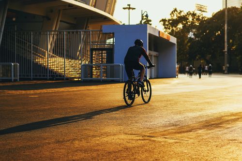 Free A cyclist enjoys a sunset ride in a vibrant urban setting, capturing the essence of recreation and travel. Stock Photo