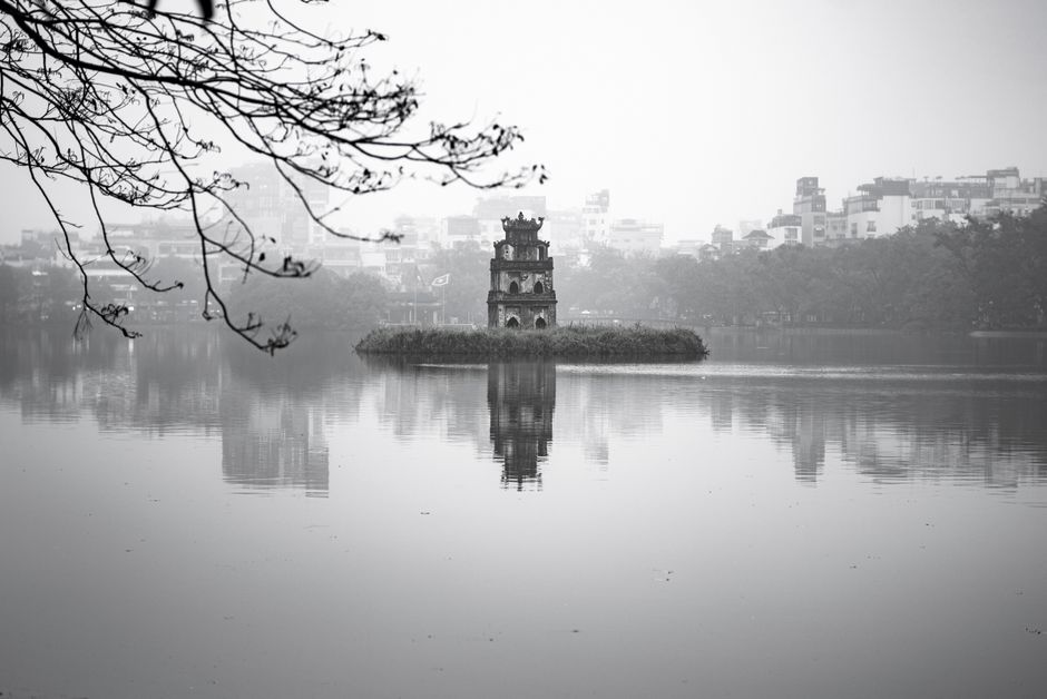 Black and white image of Turtle Tower on Hoan Kiem Lake in Hanoi with reflections.