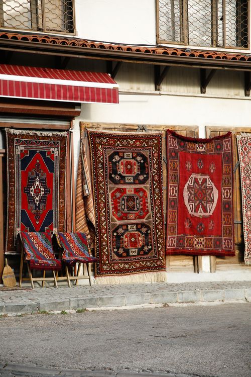 Free An array of vibrant traditional carpets hangs on a building facade, creating a cultural street scene. Stock Photo