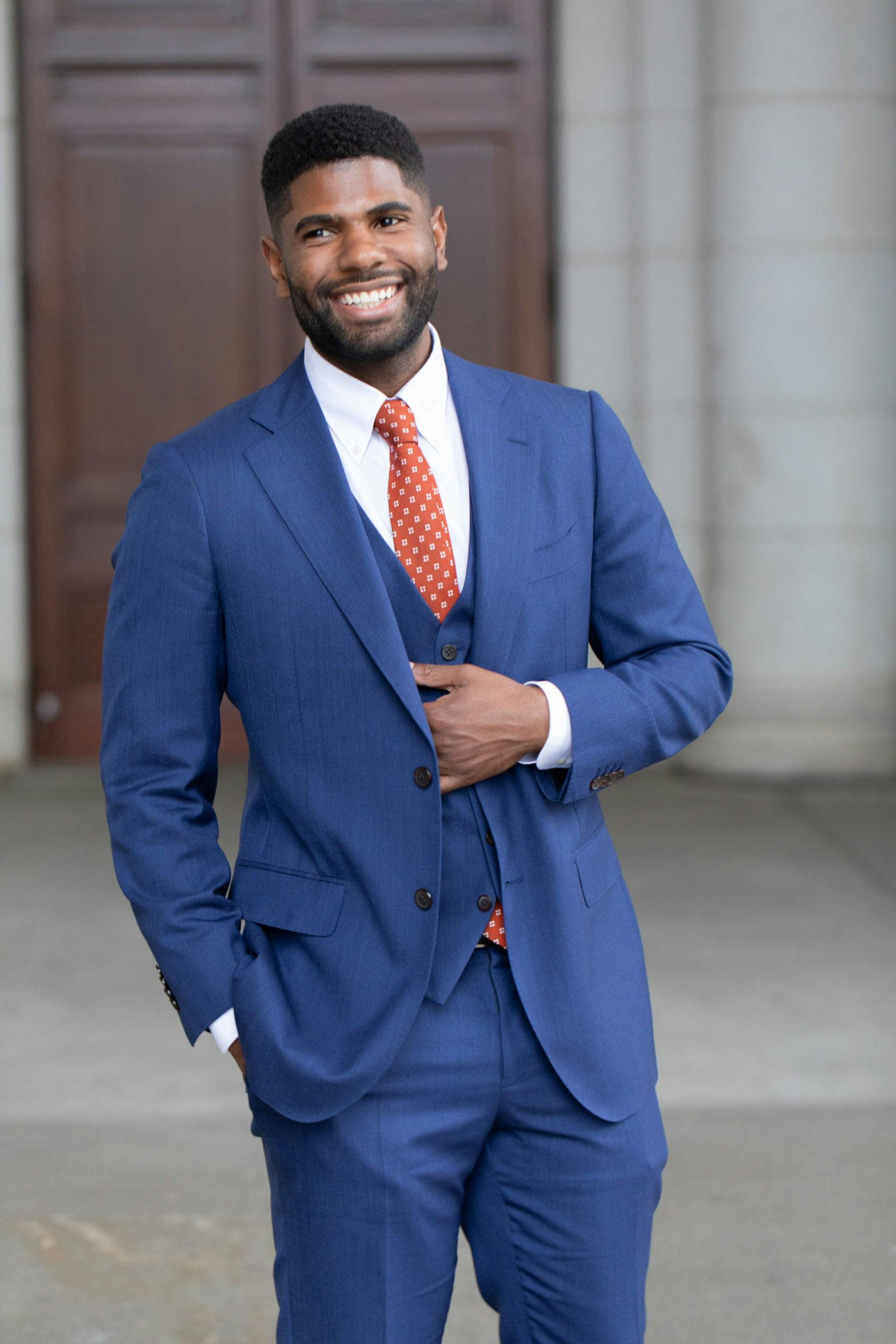 Man in blue blazer and gray dress pants standing on sidewalk during daytime  photo  Free Il Image on Unsplash