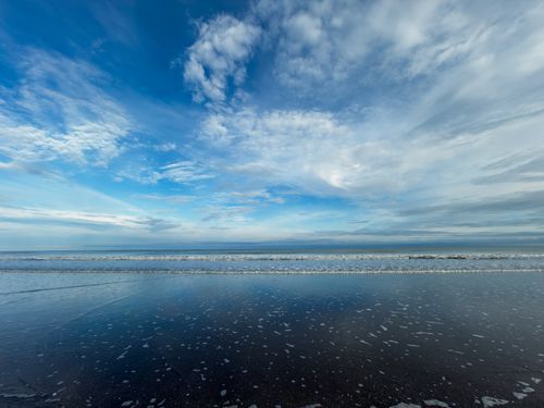 Free Serene beach view in Ecuador with reflections and dramatic sky, perfect for tranquil and nature themes. Stock Photo