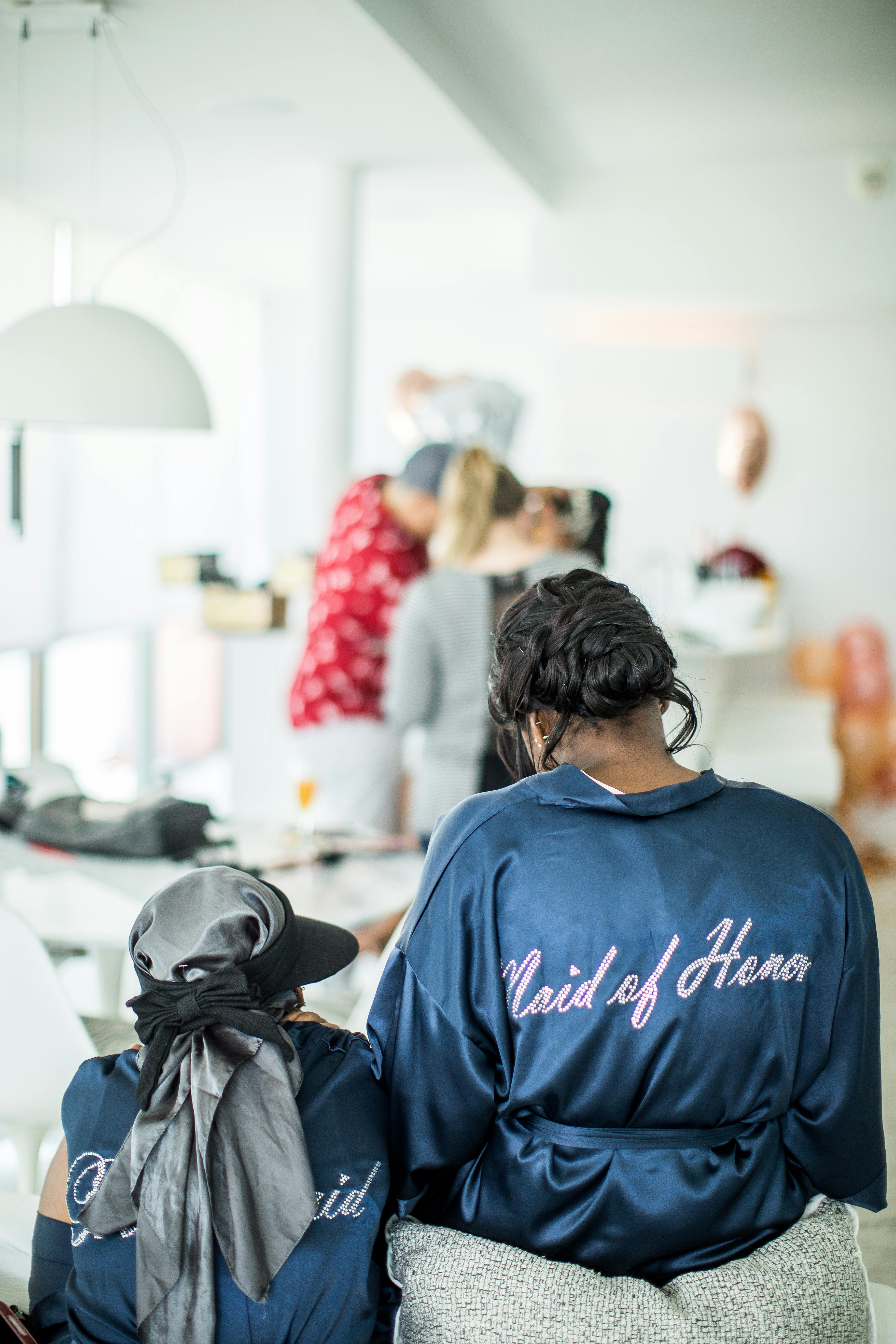 A bridal party prepares indoors, showcasing the Maid of Honor and unique robes.
