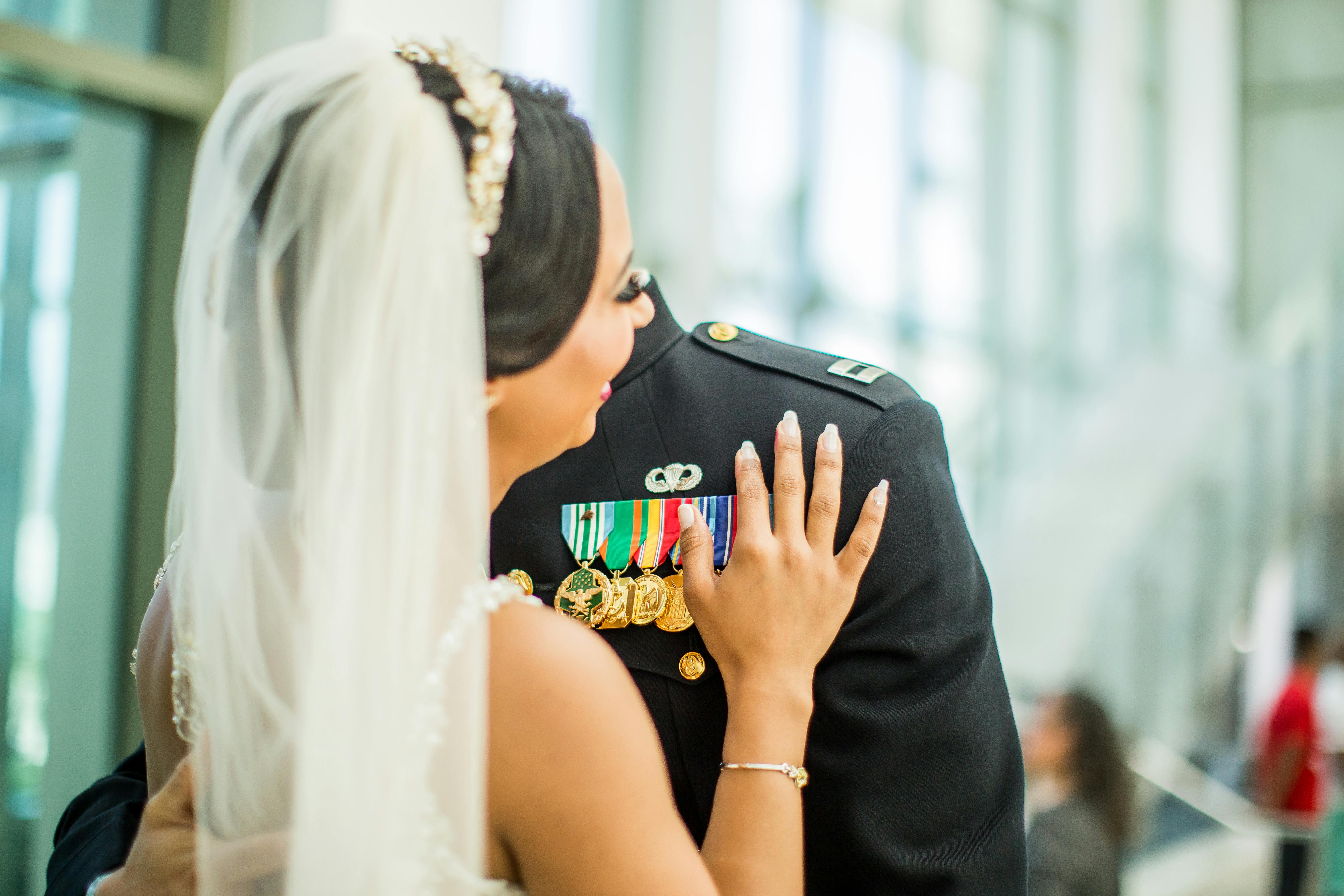 A bride and groom sharing a moment, with military uniform and medals highlighted indoors.