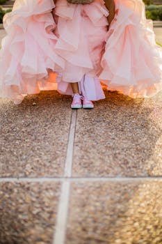 A contrasting look with a flowing pink dress and casual sneakers on a sunny day.