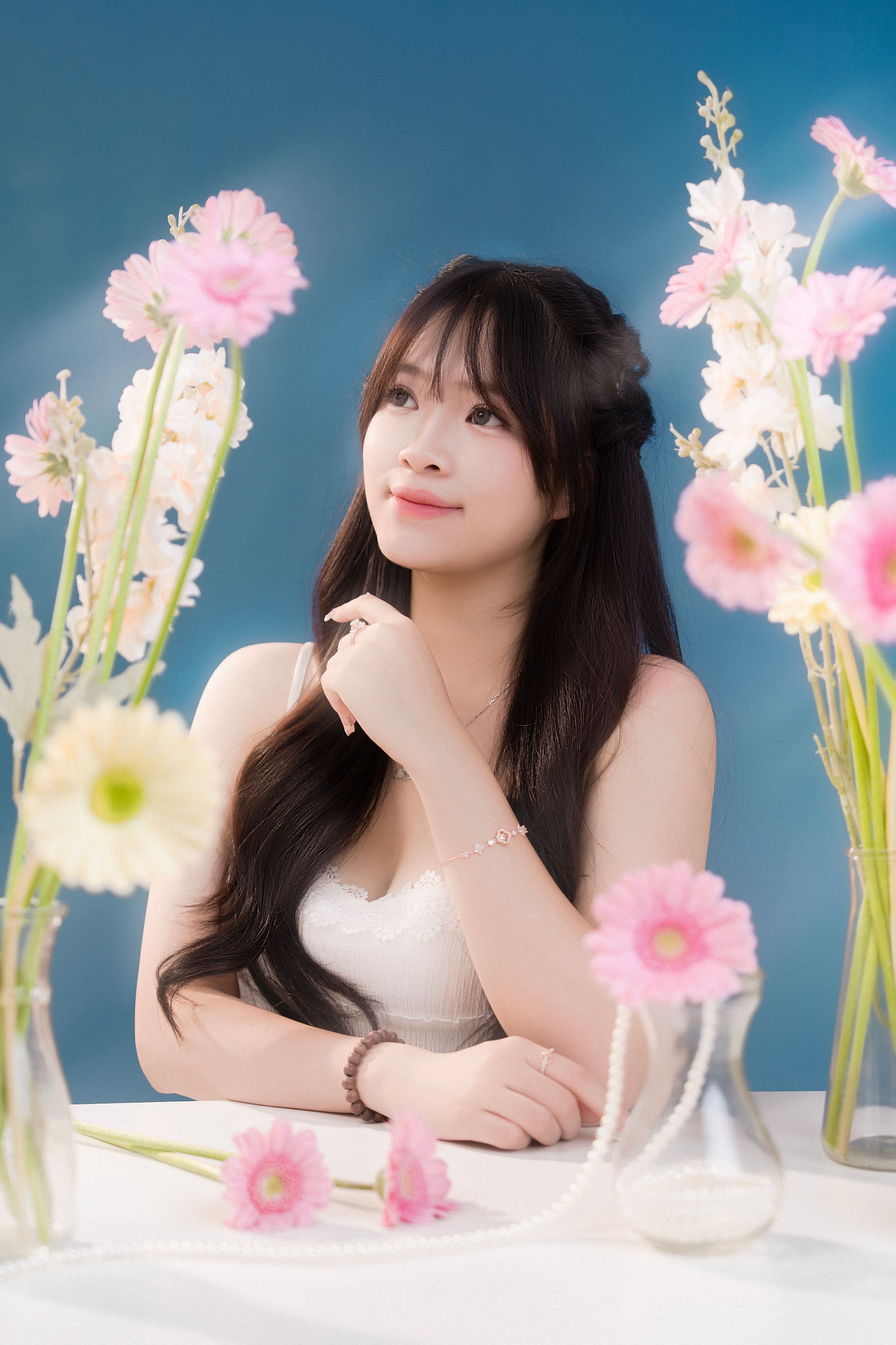 A serene portrait of a woman in a floral setting against a blue background.