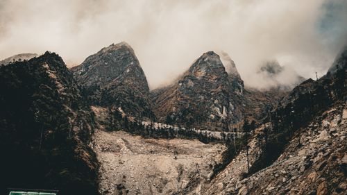 Free Dramatic mountain peaks rise through mist, creating a moody landscape scene with rugged terrain. Stock Photo