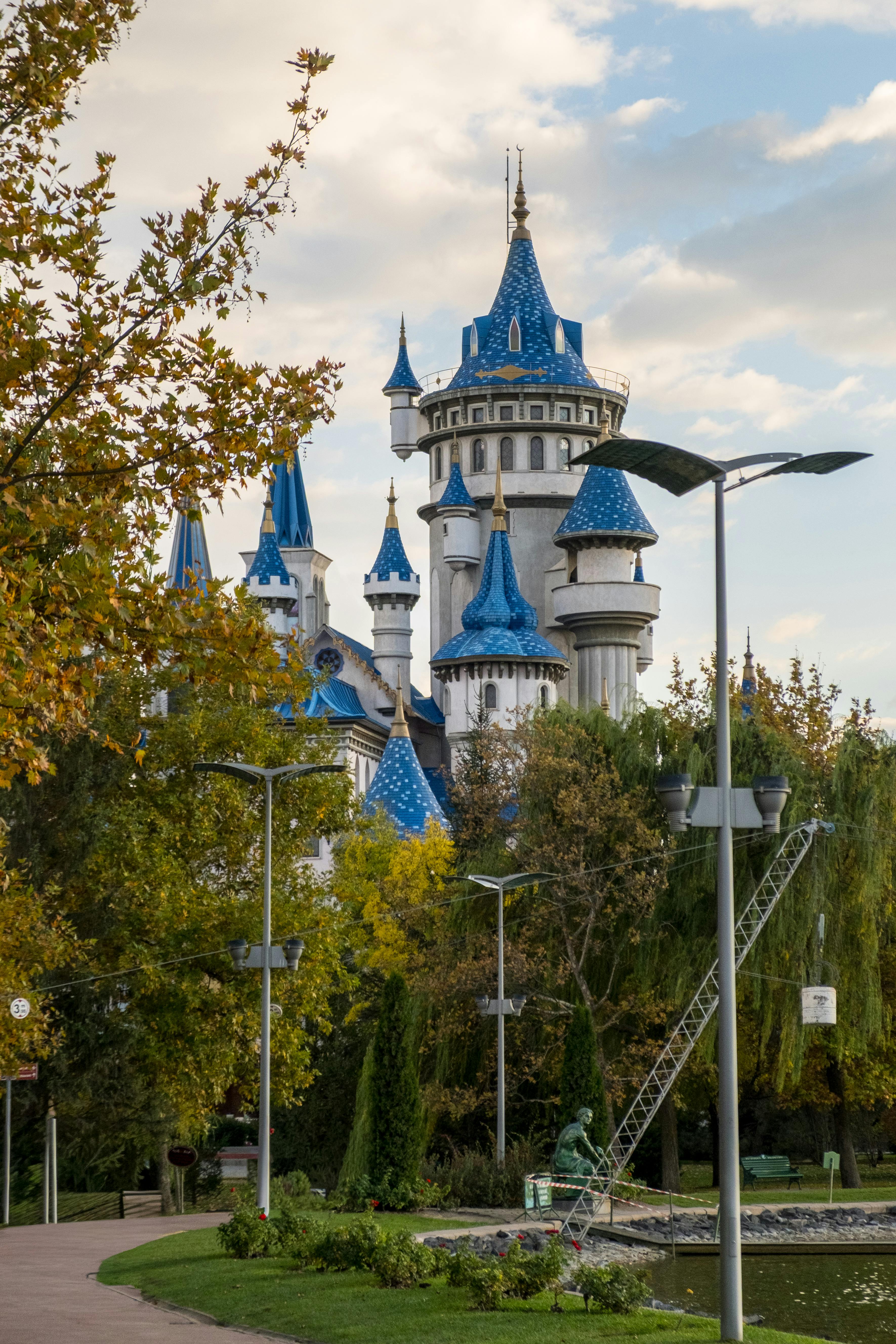A majestic fairy tale castle with blue turrets in Sazova Park, Turkey, surrounded by lush greenery.
