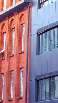 Contrast between classic red brick and modern grey metal building facades.