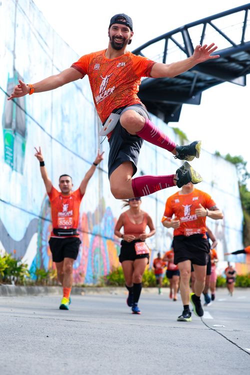 Free Runner leaping in excitement during a marathon with a graffiti wall backdrop. Stock Photo