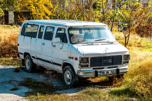 Free An old white van parked in an overgrown lot with autumn foliage. Stock Photo