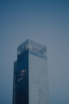 A tall modern skyscraper in Turin, Italy, rises against a twilight sky, reflecting a soft, moody ambiance.