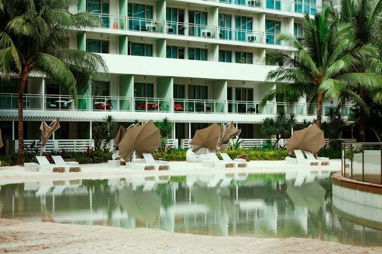 Swimming Pool With Deckchairs In Yard Of Hotel