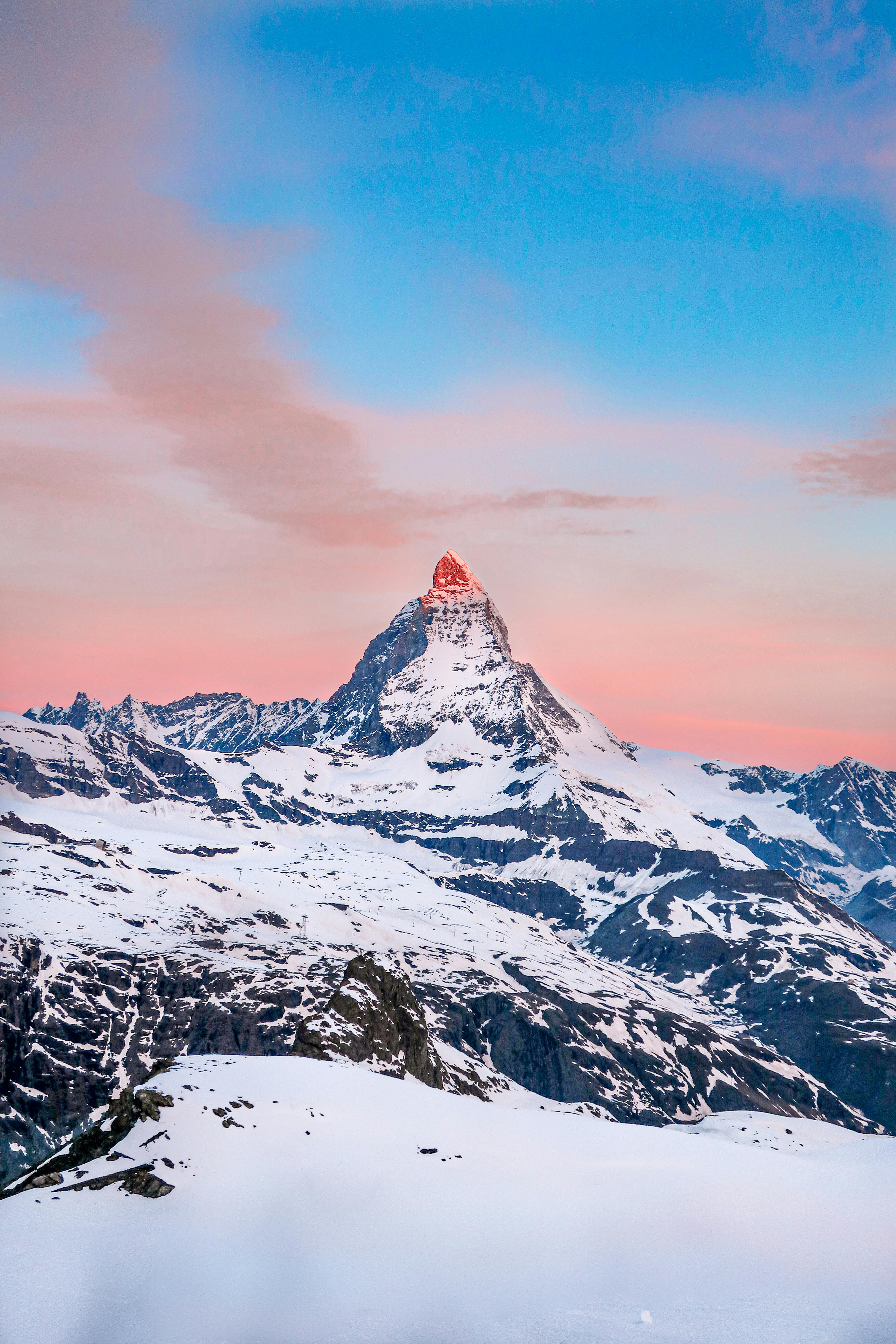 Captivating sunrise view of the Matterhorn peak in Swiss Alps with snow-capped mountains.