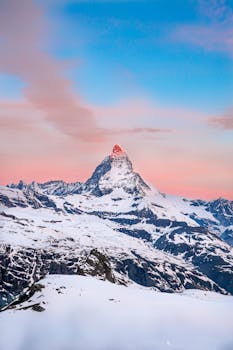 Captivating sunrise view of the Matterhorn peak in Swiss Alps with snow-capped mountains.