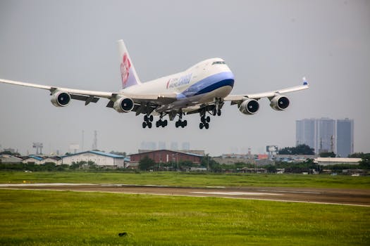Cargo aircraft landing at an airport in Banten, Indonesia, with city skyline in the background.