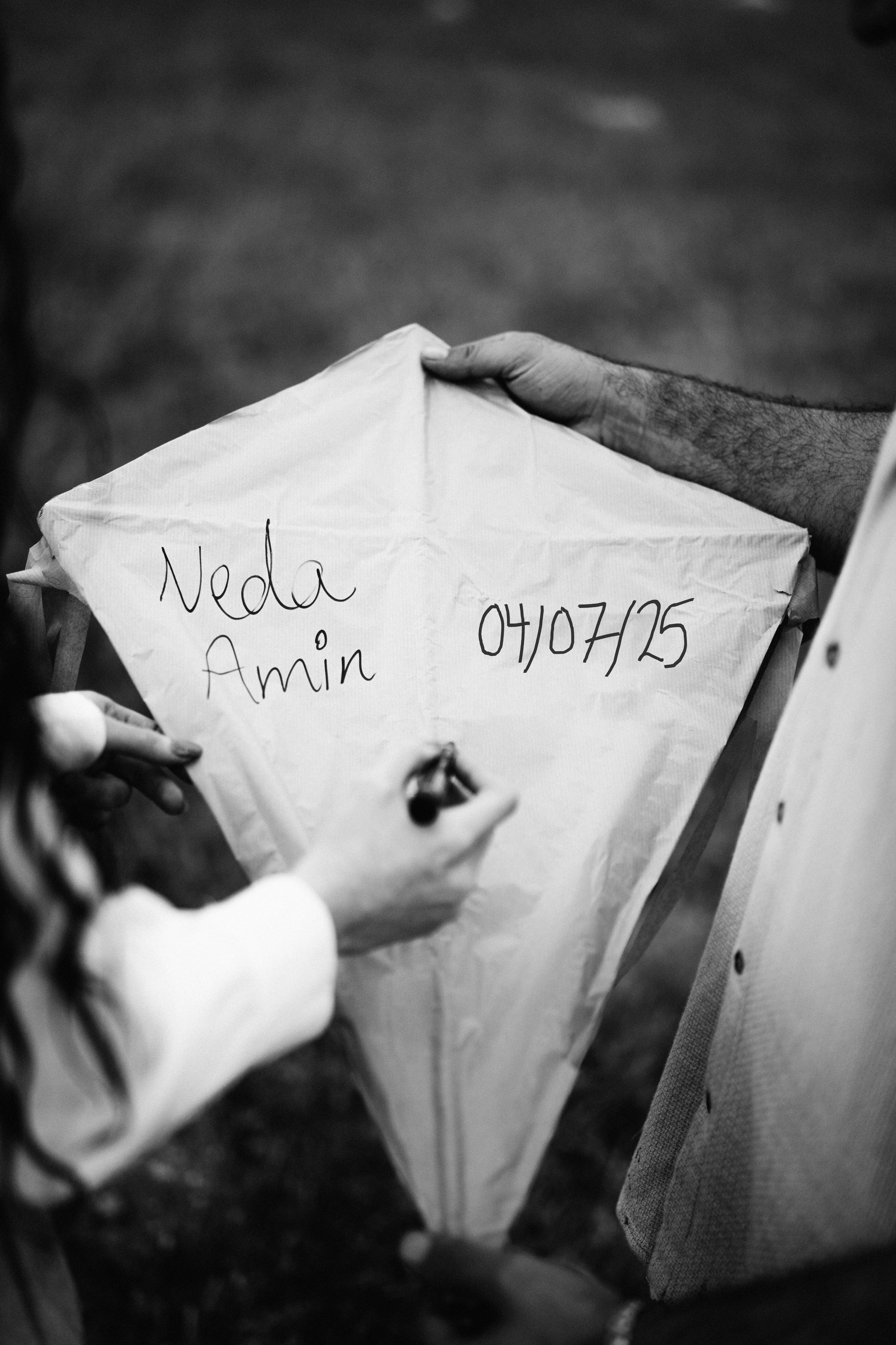 무료 야외 모임에서 흑백으로 표현된 배경 속에서 개인 텍스트가 적힌 연에 손이 서명하는 모습입니다. 스톡 사진