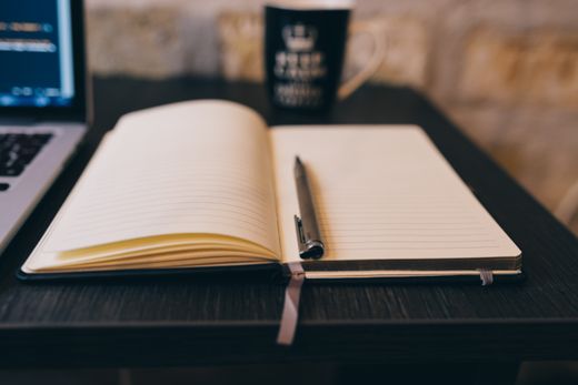 Open notebook and pen on a wooden desk — photo by Negative Space on Pexels