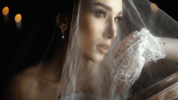 A close-up bridal portrait highlighting elegance with lace veil and soft candlelight.
