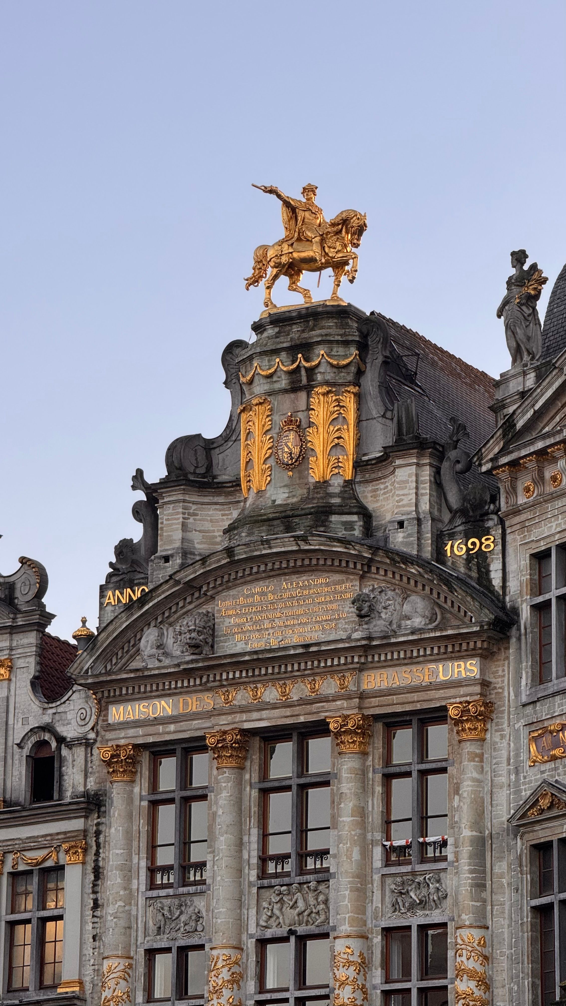 Historical building facade with golden equestrian statue in Brussels.