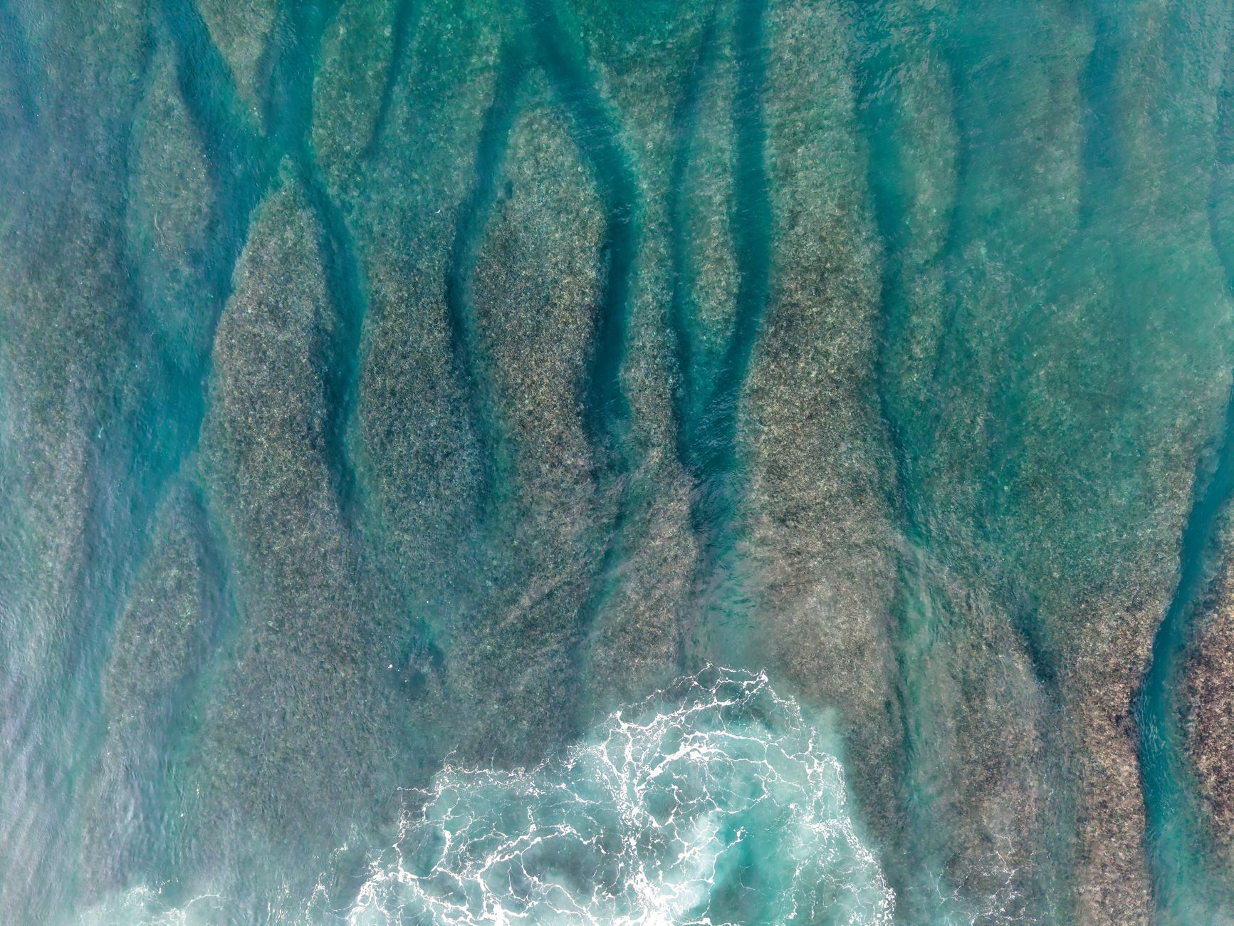 Explore the striking beauty of Bali's coral reefs and turquoise ocean waves from an aerial perspective.