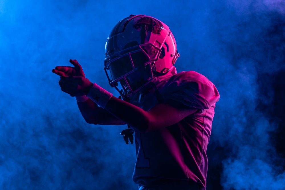 Silhouetted player in helmet and pads amid stadium smoke — photo by Willians Huerta on Pexels