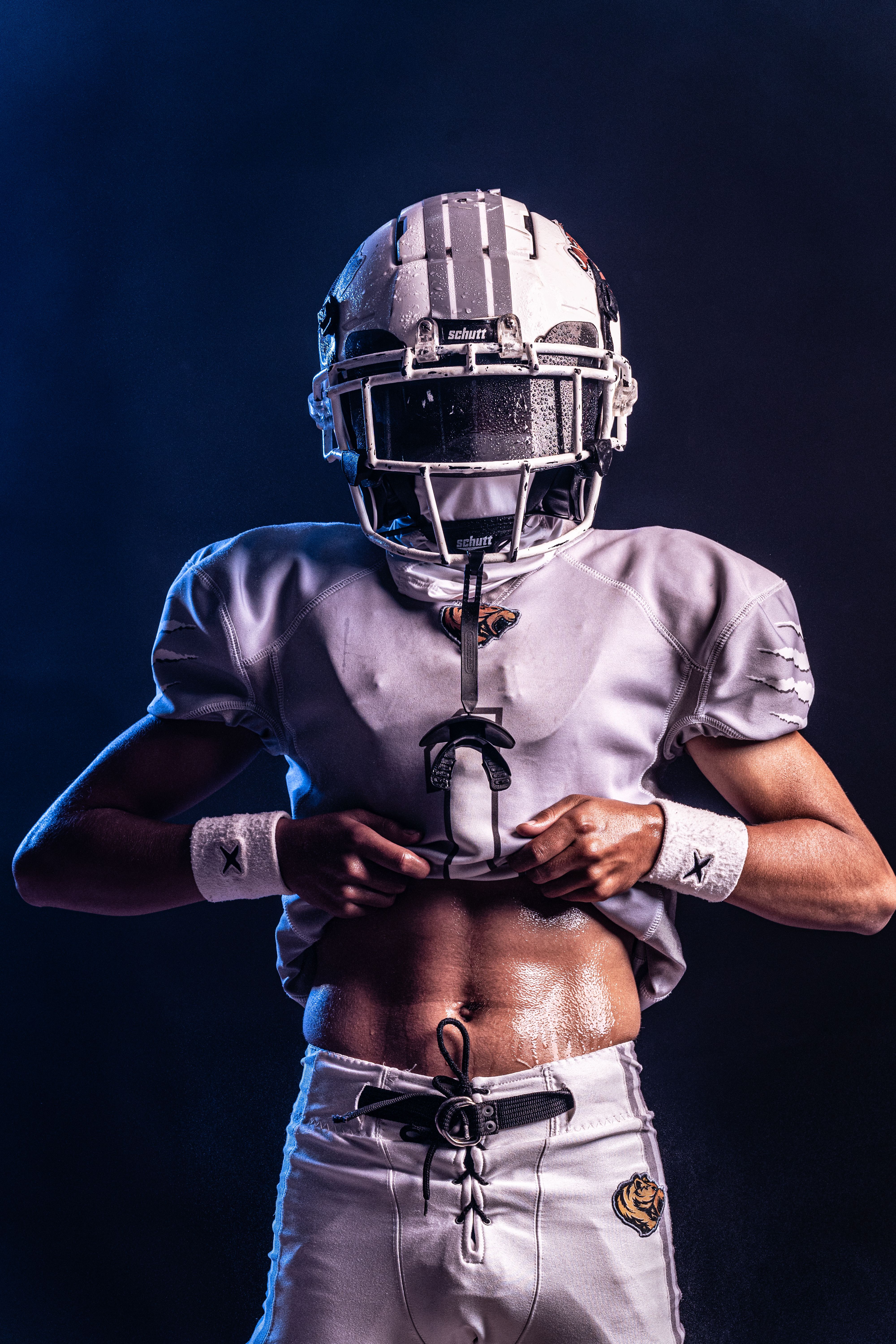 A focused football player adjusting gear, ready for action. Perfect for sports imagery.