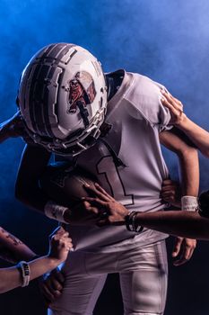 Intense football match scene with helmeted player tackled under dramatic lighting.